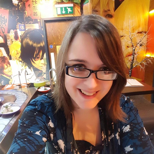 Selfie of Emma in a bright, colourful sushi restaurant with Japanese manga-style art on the walls